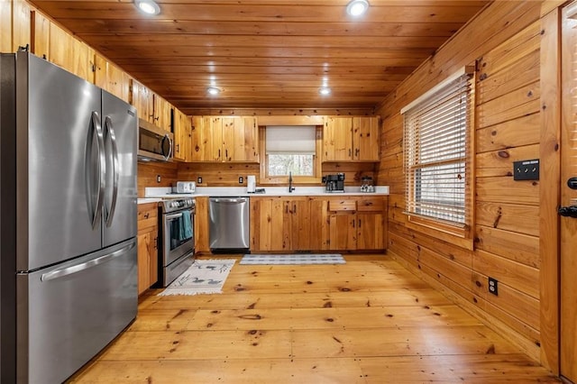 kitchen with wooden walls, a healthy amount of sunlight, light countertops, wooden ceiling, and appliances with stainless steel finishes