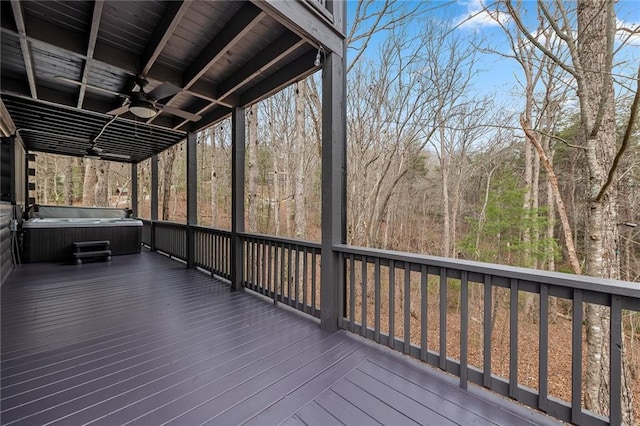 wooden deck featuring a forest view, a ceiling fan, and a hot tub