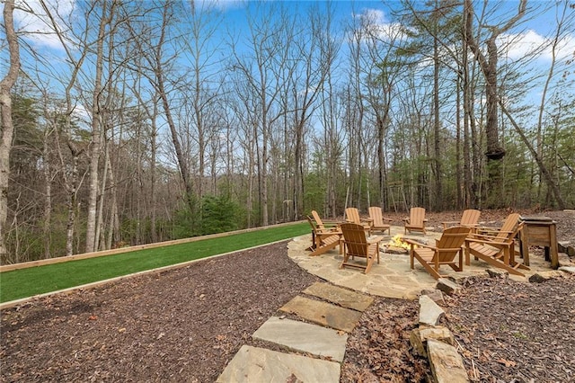 view of yard with an outdoor fire pit, a patio, and a view of trees