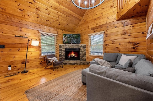 living area with wood-type flooring, wooden walls, a healthy amount of sunlight, and vaulted ceiling