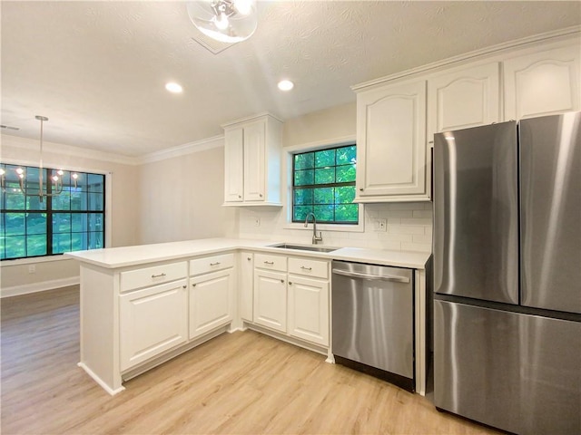 kitchen with stainless steel appliances, sink, white cabinets, light hardwood / wood-style floors, and kitchen peninsula