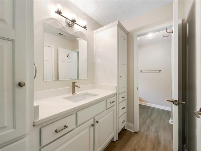 bathroom with hardwood / wood-style flooring, a textured ceiling, and vanity