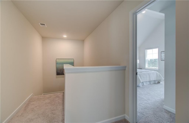 hall with carpet floors, baseboards, an upstairs landing, and visible vents