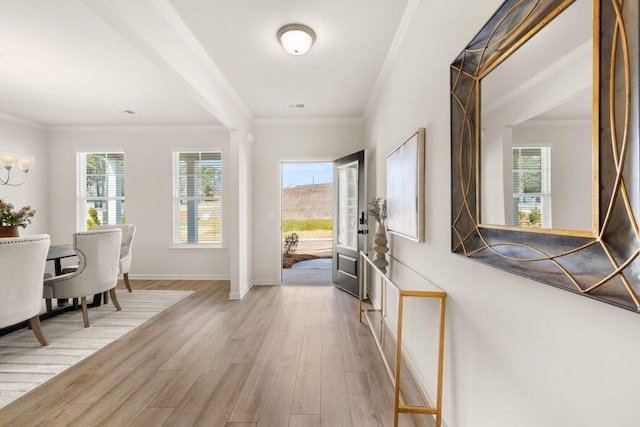 entryway with a healthy amount of sunlight, baseboards, ornamental molding, and light wood-type flooring