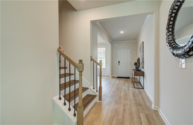 foyer with baseboards, ornamental molding, stairway, and light wood-type flooring
