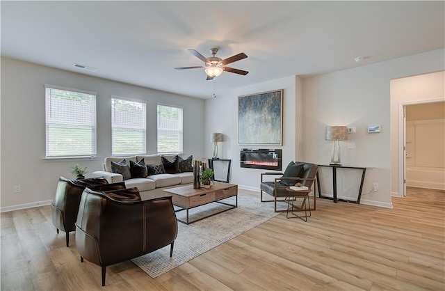 living area with baseboards, a ceiling fan, light wood-type flooring, and visible vents