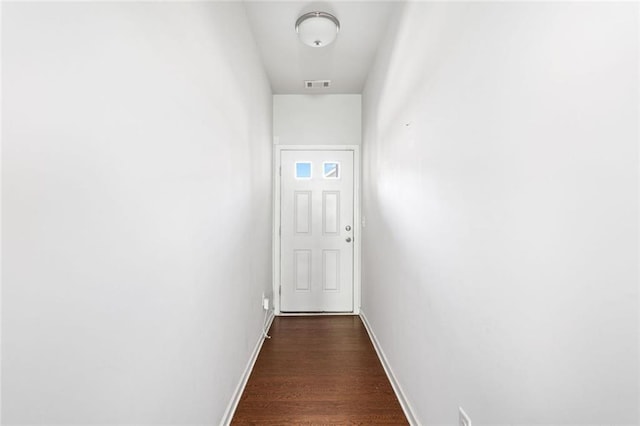 corridor featuring baseboards, dark wood finished floors, and visible vents