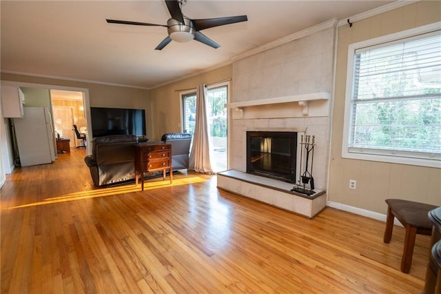 living room featuring a fireplace, hardwood / wood-style floors, ceiling fan, and crown molding