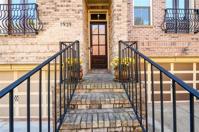 doorway to property with a garage and brick siding