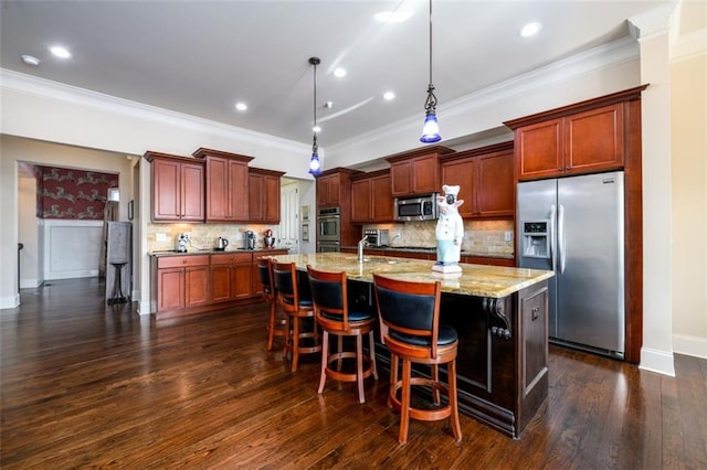 kitchen with a breakfast bar area, hanging light fixtures, light stone countertops, a kitchen island with sink, and stainless steel appliances