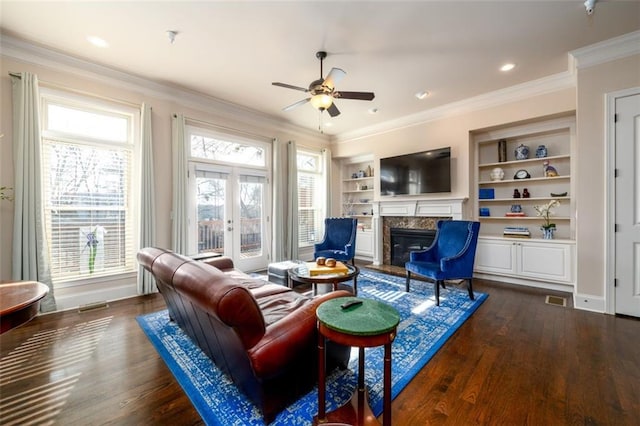 living room with built in features, dark wood-style floors, french doors, a premium fireplace, and ornamental molding