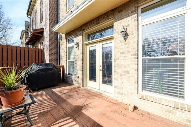 wooden terrace featuring a grill, fence, and french doors