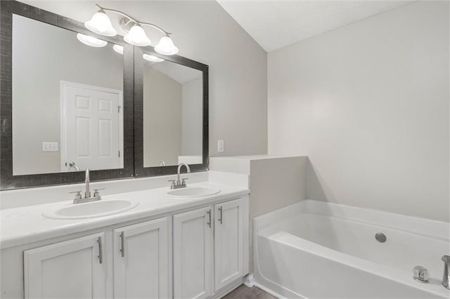 bathroom featuring vanity, lofted ceiling, and a tub