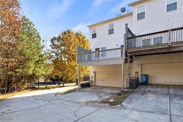 rear view of house featuring a balcony, a garage, and central AC unit