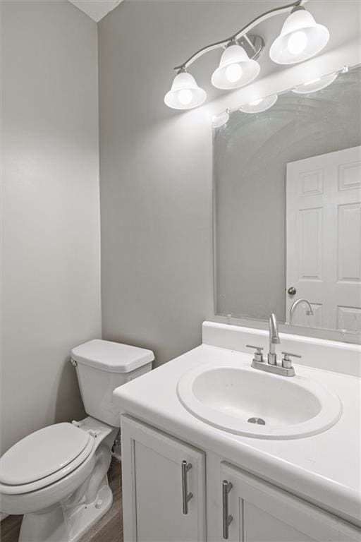 bathroom with hardwood / wood-style floors, vanity, and toilet