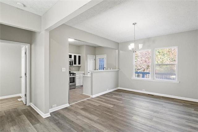 unfurnished dining area with hardwood / wood-style floors, a notable chandelier, and a textured ceiling