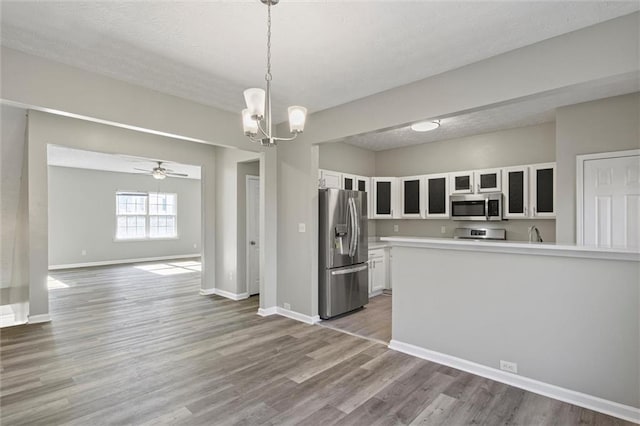 kitchen featuring white cabinets, decorative light fixtures, light hardwood / wood-style floors, and appliances with stainless steel finishes