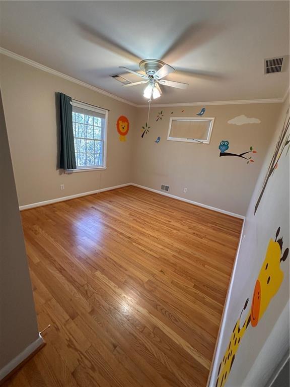 unfurnished room featuring baseboards, visible vents, ornamental molding, and light wood-style flooring