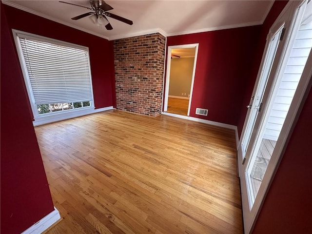 spare room featuring crown molding, ceiling fan, light wood-style floors, baseboards, and visible vents