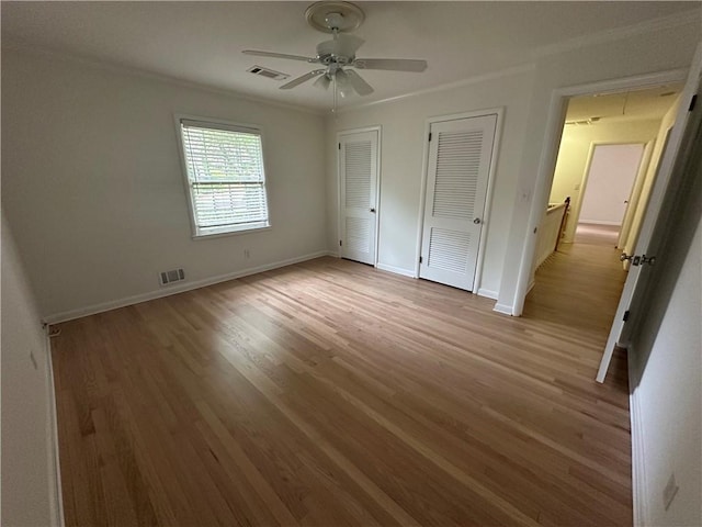 6542 Cherry Tree Ln, Atlanta, GA 30328 - unfurnished bedroom featuring two closets, wood finished floors, crown molding, ceiling fan, and attic access