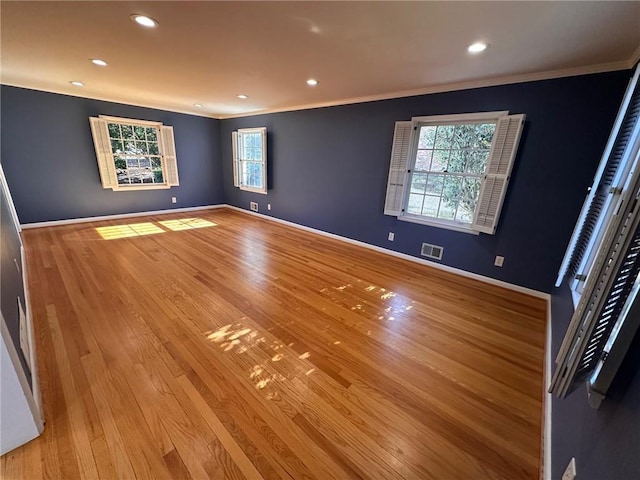 unfurnished room with baseboards, ornamental molding, light wood-style flooring, and visible vents