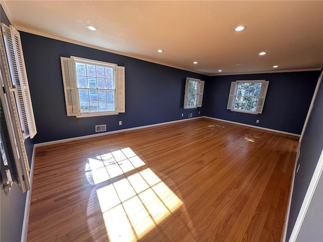 empty room featuring visible vents, ornamental molding, wood finished floors, and recessed lighting