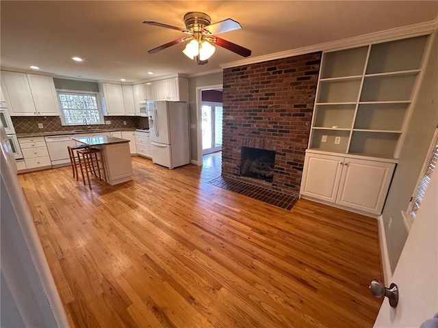 kitchen featuring ornamental molding, white appliances, ceiling fan, white cabinetry, and a sink
