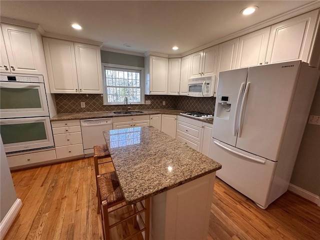 kitchen with a sink, light wood-type flooring, white appliances, and white cabinetry