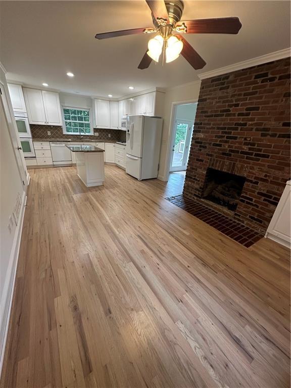 6542 Cherry Tree Ln, Atlanta, GA 30328 - kitchen with white appliances, backsplash, light wood-style flooring, a ceiling fan, and white cabinetry