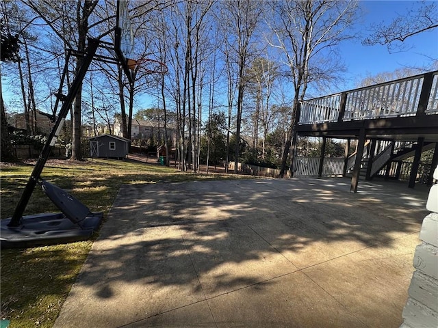 exterior space featuring fence, a deck, stairs, an outbuilding, and driveway