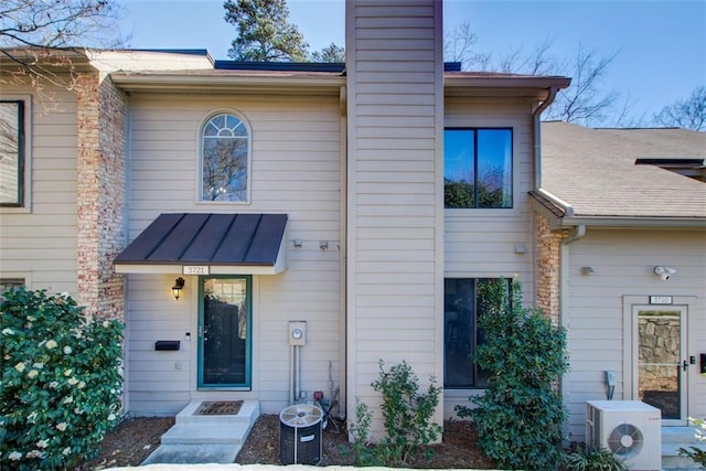 view of front of house with ac unit, a chimney, central air condition unit, a standing seam roof, and metal roof