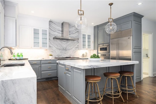 kitchen featuring sink, a kitchen island, wall chimney range hood, and appliances with stainless steel finishes