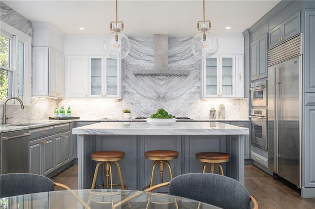 kitchen with sink, stainless steel appliances, white cabinets, a kitchen island, and wall chimney exhaust hood