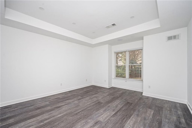 unfurnished room featuring dark hardwood / wood-style floors and a raised ceiling