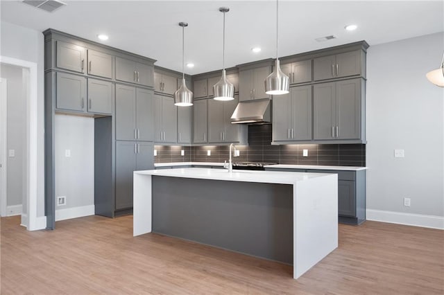 kitchen with decorative light fixtures, gray cabinetry, light hardwood / wood-style floors, and extractor fan