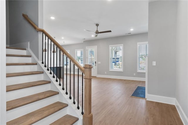 stairs featuring hardwood / wood-style flooring and ceiling fan