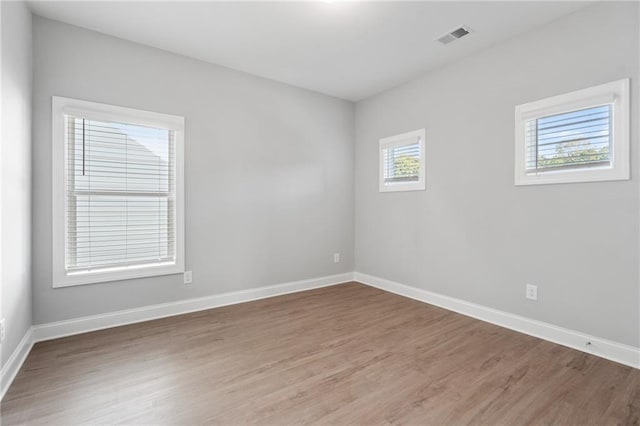 empty room with dark hardwood / wood-style flooring and a wealth of natural light