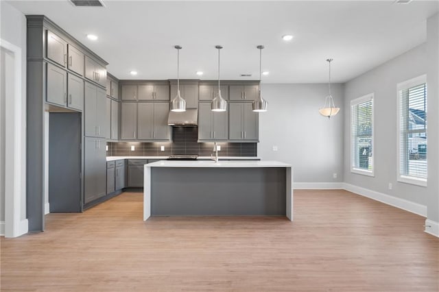 kitchen with gray cabinets, hanging light fixtures, and light hardwood / wood-style floors