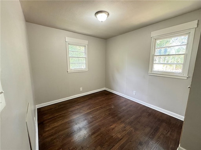 unfurnished room featuring a healthy amount of sunlight and dark hardwood / wood-style floors