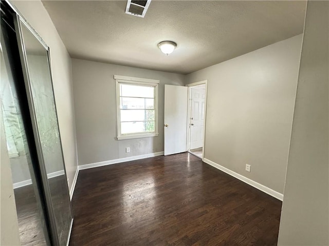 unfurnished bedroom featuring a textured ceiling and dark wood-type flooring