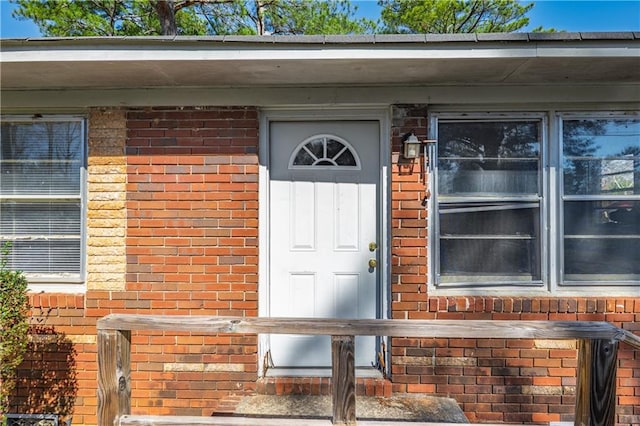 view of exterior entry featuring brick siding