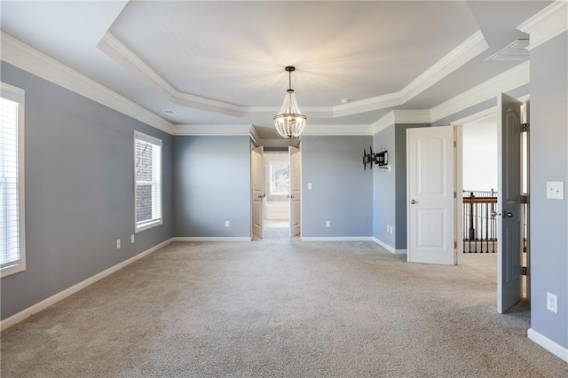 spare room featuring carpet floors, a notable chandelier, crown molding, a raised ceiling, and baseboards