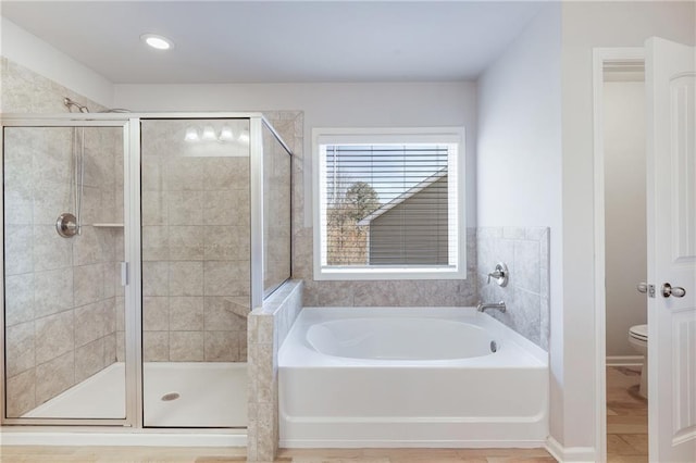 bathroom featuring toilet, a stall shower, and a garden tub