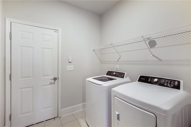 washroom featuring laundry area, light tile patterned floors, baseboards, and washer and clothes dryer