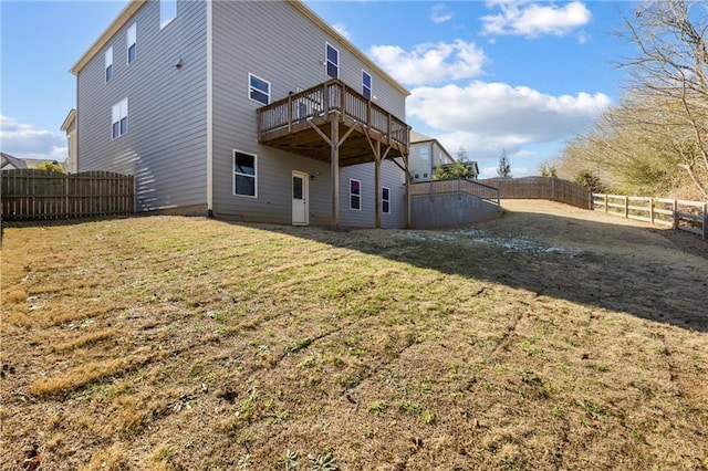 back of property featuring a fenced backyard, a deck, and a lawn