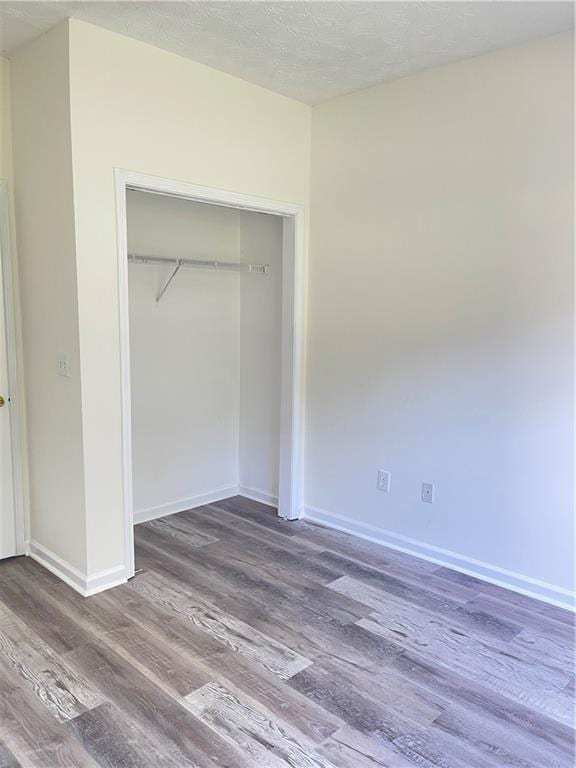 203 Sea Marsh Ct, Fayetteville, GA 30215 - unfurnished bedroom with wood finished floors, a closet, baseboards, and a textured ceiling