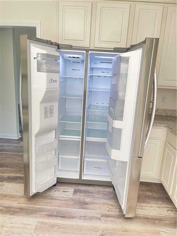 203 Sea Marsh Ct, Fayetteville, GA 30215 - detailed view of freestanding refrigerator, light wood finished floors, and light stone counters