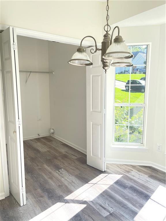 203 Sea Marsh Ct, Fayetteville, GA 30215 - unfurnished dining area featuring wood finished floors, baseboards, healthy amount of natural light, and a chandelier
