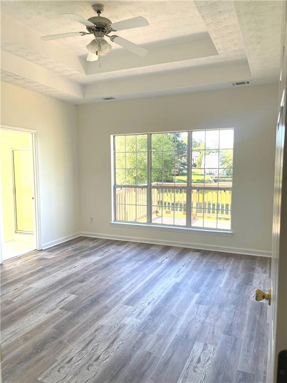 203 Sea Marsh Ct, Fayetteville, GA 30215 - empty room featuring a tray ceiling, healthy amount of natural light, wood finished floors, and baseboards