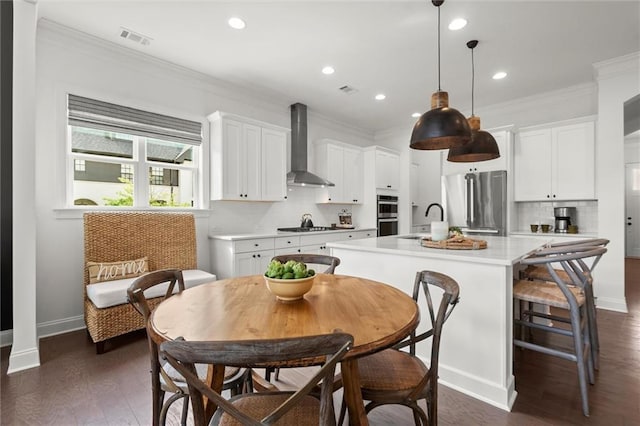 635 Opera Ln, Alpharetta, GA 30009 - kitchen with wall chimney range hood, appliances with stainless steel finishes, an island with sink, light countertops, and decorative backsplash
